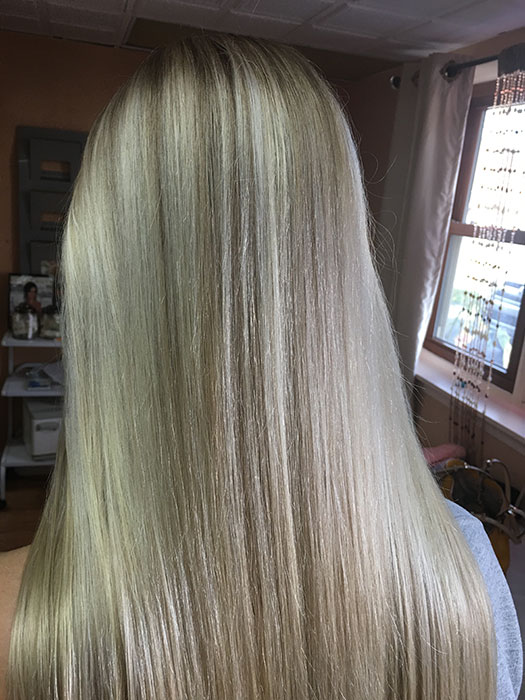 Back view of blonde woman's straight hair.